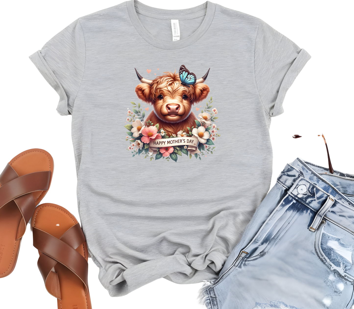 Mother’s Day Inspired Woman’s T-Shirt, featuring a Highland Cow surrounded by beautiful flowers a butterfly and a “Happy Mother’s Day” message.