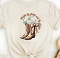 Faith Based Woman’s T-Shirt Featuring Cowgirl boots, White Flowers and The Message “Walk by faith not by sight!”