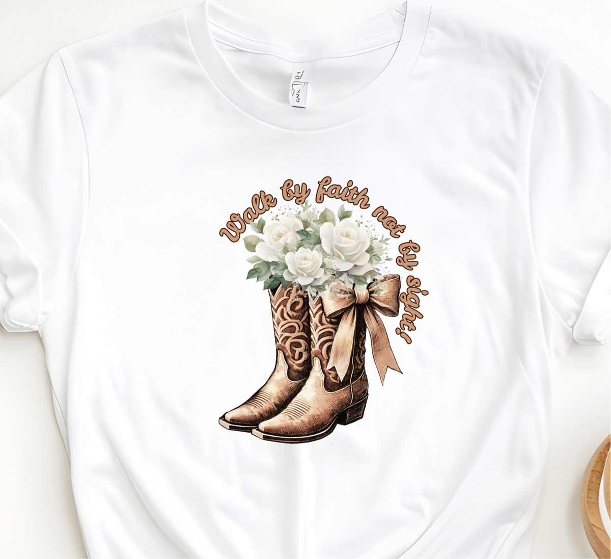 Faith Based Woman’s T-Shirt Featuring Cowgirl boots, White Flowers and The Message “Walk by faith not by sight!”