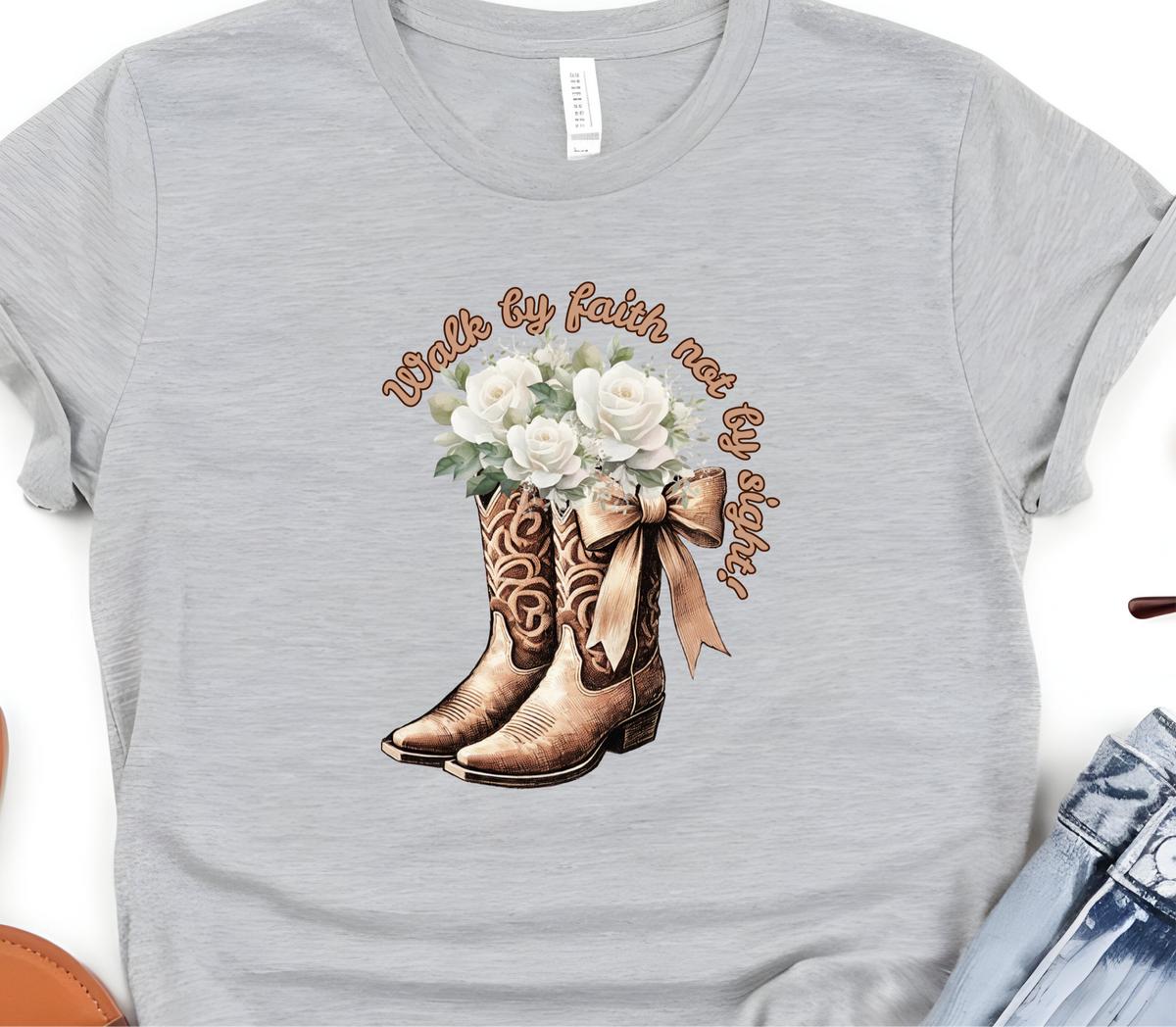 Faith Based Woman’s T-Shirt Featuring Cowgirl boots, White Flowers and The Message “Walk by faith not by sight!”