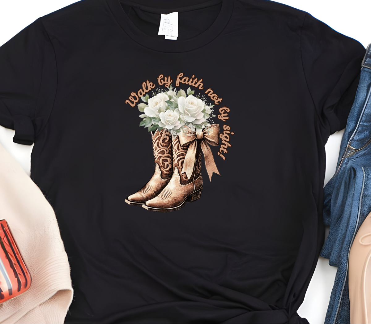Faith Based Woman’s T-Shirt Featuring Cowgirl boots, White Flowers and The Message “Walk by faith not by sight!”