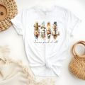 Faith Based Woman’s T-Shirt, featuring beautiful graphic design of a cross, bible, and a lamb with a crown of flowers with the message Jesus Paid It All”.