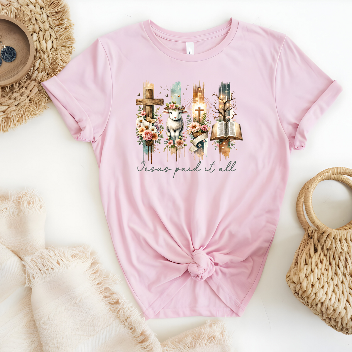 Faith Based Woman’s T-Shirt, featuring beautiful graphic design of a cross, bible, and a lamb with a crown of flowers with the message Jesus Paid It All”.