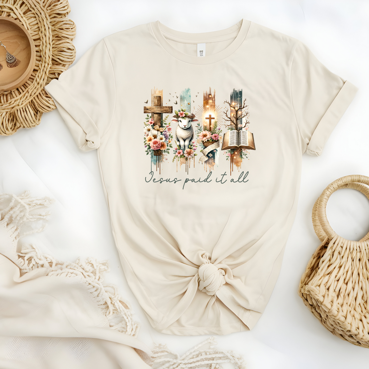 Faith Based Woman’s T-Shirt, featuring beautiful graphic design of a cross, bible, and a lamb with a crown of flowers with the message Jesus Paid It All”.